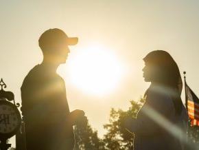 Silhouette of two students facing each other outside during sunset